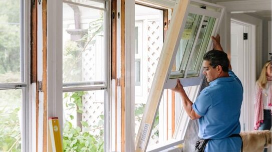 Installer fitting a new replacement window in a home